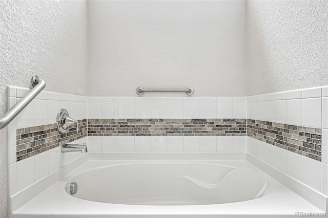 full bathroom featuring a textured wall and a bath