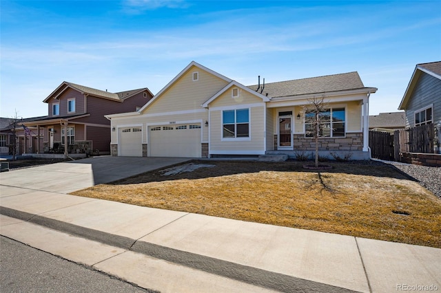 view of front of home with stone siding, fence, an attached garage, and concrete driveway