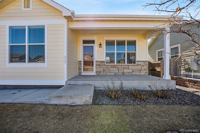 entrance to property featuring stone siding and a porch