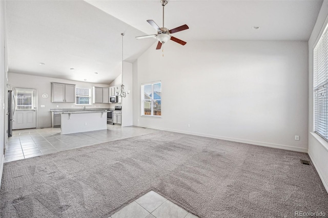 unfurnished living room with light tile patterned floors, visible vents, a ceiling fan, light colored carpet, and high vaulted ceiling