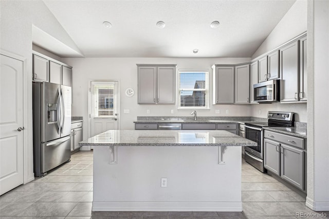 kitchen featuring lofted ceiling, appliances with stainless steel finishes, and gray cabinetry