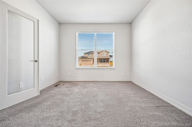 unfurnished room featuring carpet, visible vents, and baseboards