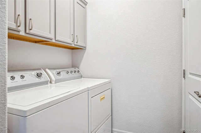 laundry area with cabinet space, washer and dryer, and a textured wall