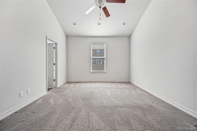 empty room featuring a textured wall, carpet floors, a ceiling fan, and baseboards