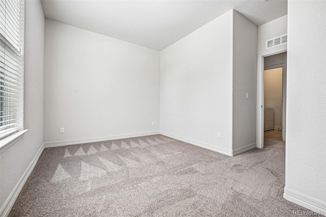 carpeted spare room with visible vents and baseboards