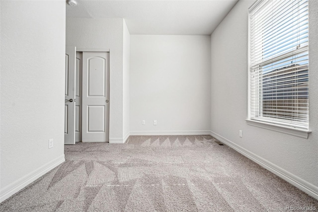 empty room featuring carpet flooring, visible vents, and baseboards