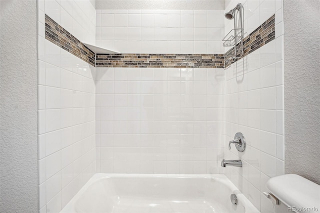 full bathroom featuring tub / shower combination, a textured wall, and toilet