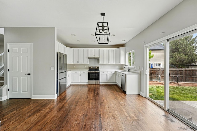 1248 Button Rock Dr, Longmont, CO 80504 - kitchen with appliances with stainless steel finishes, dark wood-type flooring, light countertops, white cabinetry, and baseboards