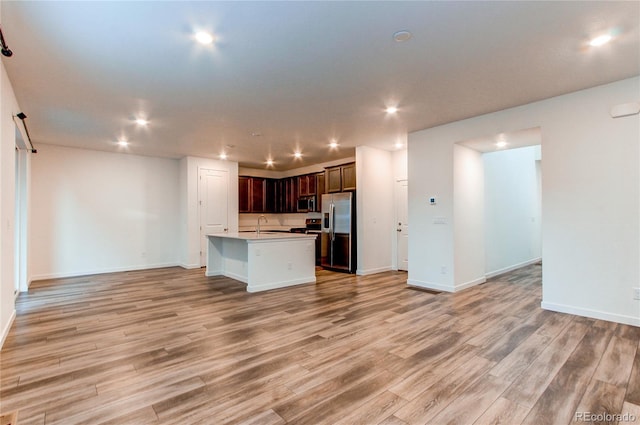 kitchen with sink, an island with sink, appliances with stainless steel finishes, and light hardwood / wood-style flooring