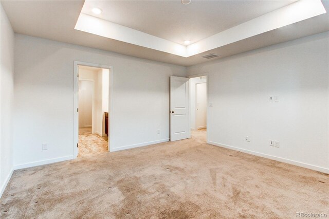 carpeted empty room with a raised ceiling