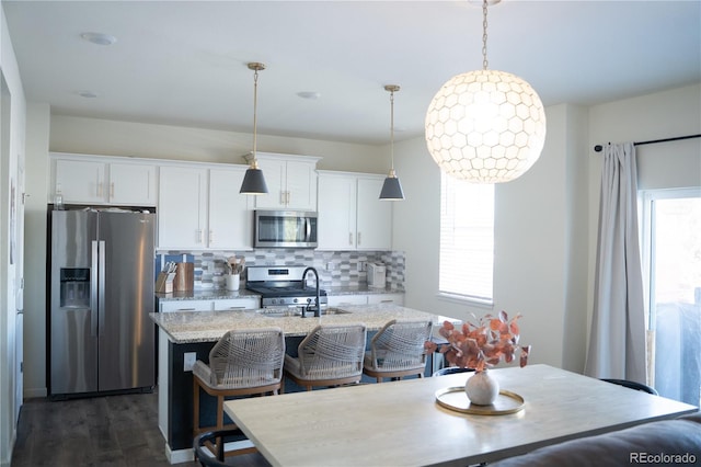 kitchen featuring stainless steel appliances, white cabinetry, sink, and a center island with sink