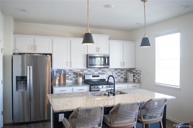 kitchen with hanging light fixtures, a center island with sink, white cabinets, and appliances with stainless steel finishes