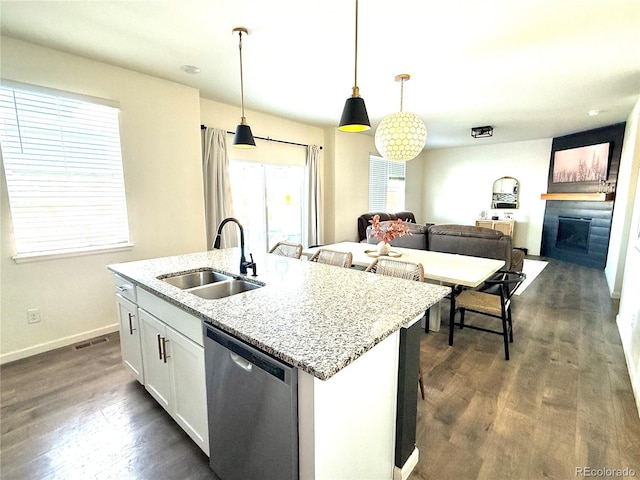 kitchen with pendant lighting, white cabinetry, dishwasher, sink, and light stone counters