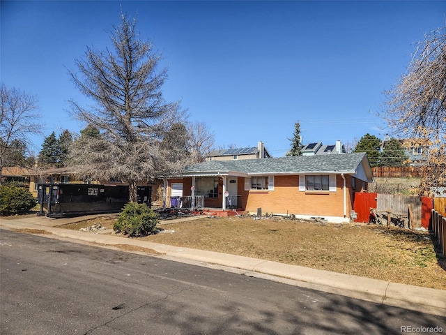 ranch-style home with a porch, fence, and brick siding