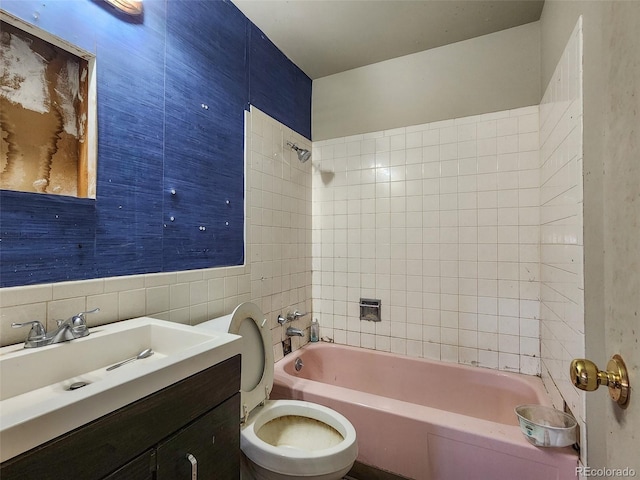 bathroom featuring tub / shower combination, toilet, tile walls, and vanity