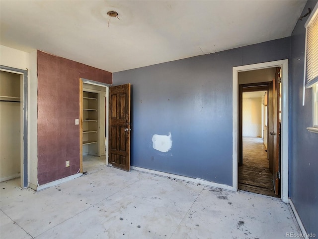 unfurnished bedroom featuring a closet, baseboards, and concrete flooring