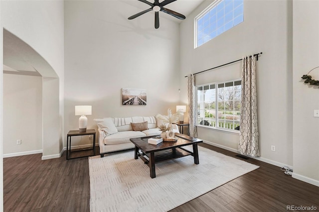 living room with plenty of natural light, baseboards, a high ceiling, and a ceiling fan
