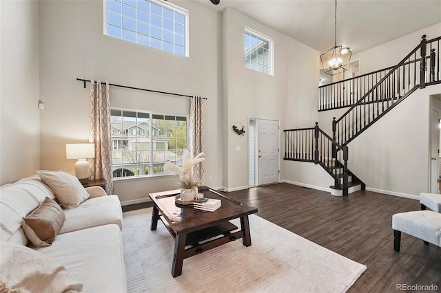 living room featuring dark wood-style flooring, stairs, a chandelier, and a healthy amount of sunlight