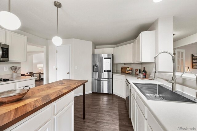 kitchen with butcher block counters, dark wood-style floors, white cabinets, a sink, and appliances with stainless steel finishes