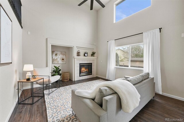 living area featuring a ceiling fan, a high ceiling, a wealth of natural light, and wood finished floors