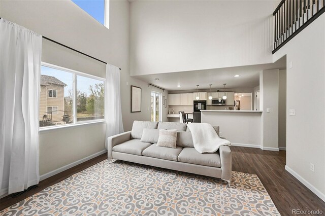 living room with baseboards, a high ceiling, dark wood-style flooring, and visible vents
