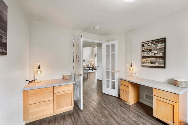 unfurnished office with built in desk, french doors, baseboards, dark wood-type flooring, and visible vents
