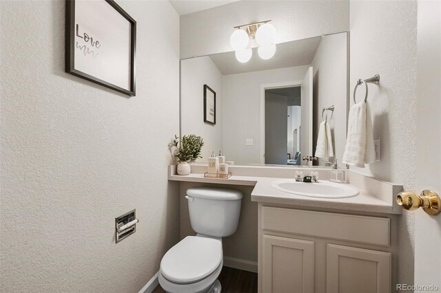 half bath featuring vanity and toilet