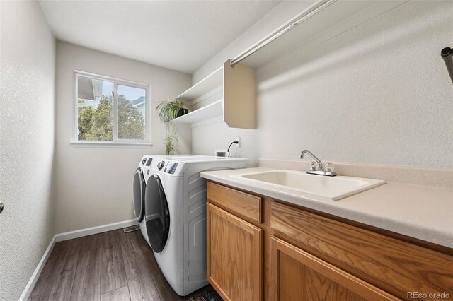 washroom featuring cabinet space, a sink, separate washer and dryer, baseboards, and dark wood-style floors