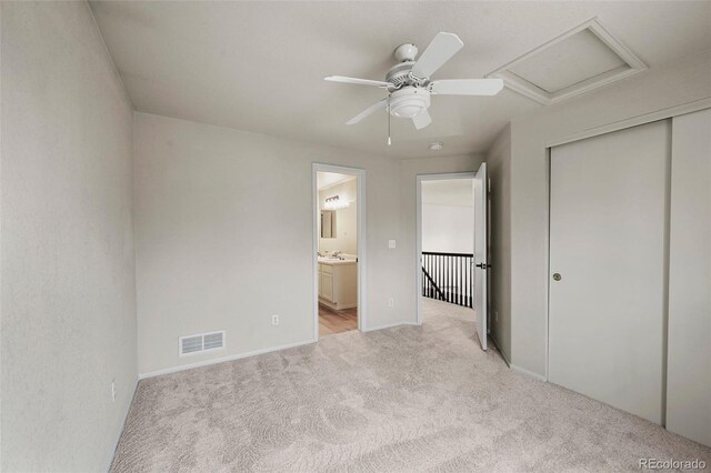 unfurnished bedroom with light colored carpet, attic access, baseboards, visible vents, and a closet