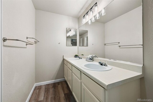bathroom with a sink, baseboards, double vanity, and wood finished floors