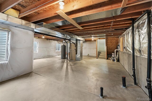 basement featuring heating unit, stairway, and gas water heater