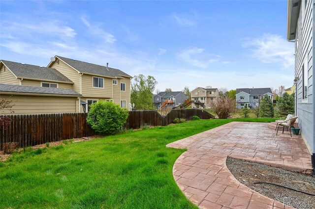 view of yard featuring a patio, a fenced backyard, and a residential view