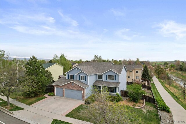 traditional home with brick siding, roof with shingles, fence, and concrete driveway