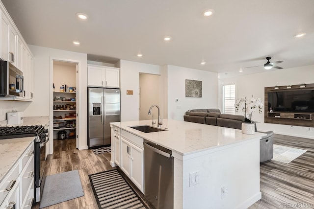 kitchen with white cabinetry, stainless steel appliances, sink, and a kitchen island with sink