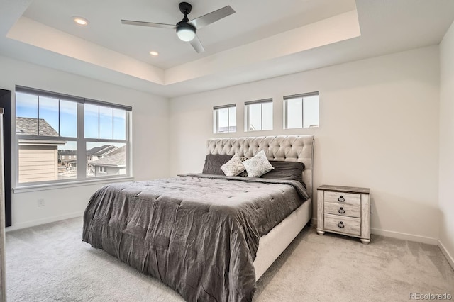 bedroom featuring multiple windows, a tray ceiling, and light carpet