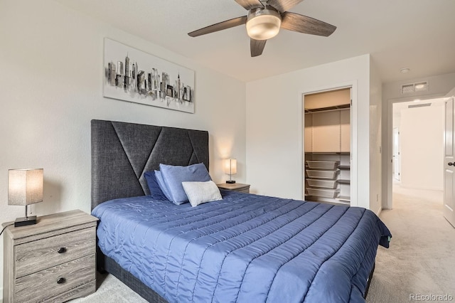 bedroom with ceiling fan, a spacious closet, a closet, and light carpet