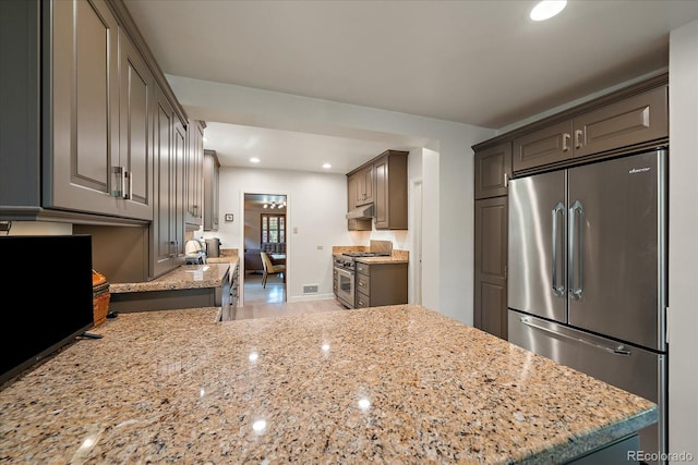 1040 N Kearney St, Denver, CO 80220 - kitchen with high quality appliances, light stone countertops, under cabinet range hood, recessed lighting, and a peninsula