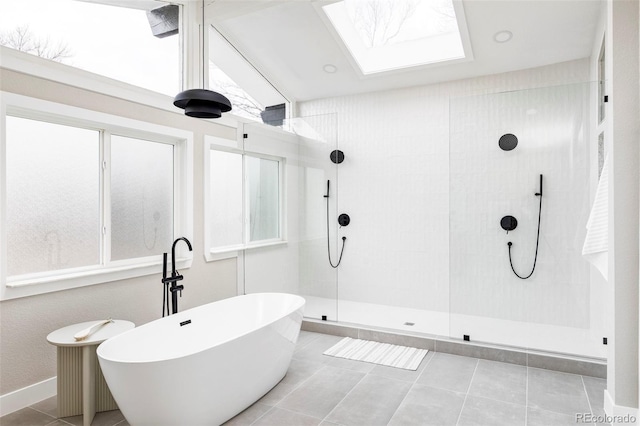 bathroom with a skylight, tile patterned flooring, and shower with separate bathtub