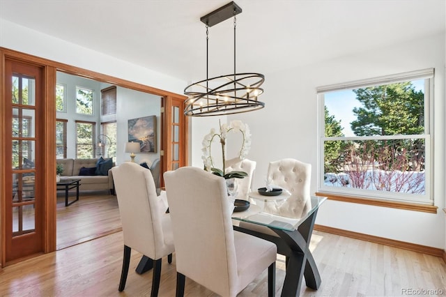 dining area with light wood-type flooring, an inviting chandelier, and a healthy amount of sunlight