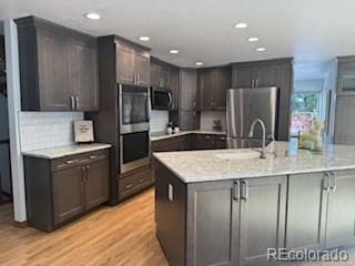 kitchen with sink, stainless steel appliances, tasteful backsplash, light hardwood / wood-style flooring, and dark brown cabinets