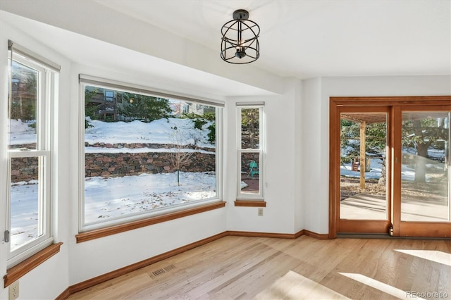 interior space with a healthy amount of sunlight, light hardwood / wood-style floors, and an inviting chandelier