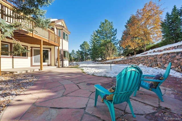 snow covered patio featuring a wooden deck