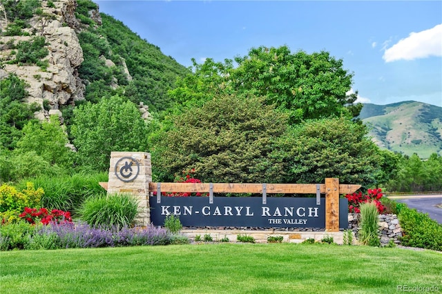 community sign with a mountain view and a yard