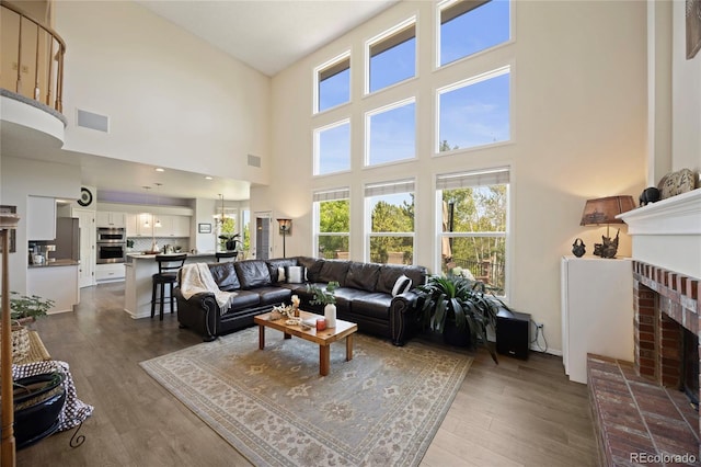 10 Sand Cherry, Littleton, CO 80127 - living area with dark wood-type flooring, a towering ceiling, healthy amount of natural light, and a fireplace