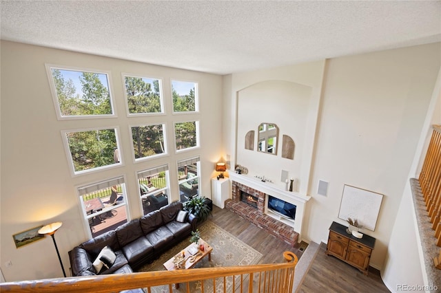 10 Sand Cherry, Littleton, CO 80127 - living area featuring a brick fireplace, wood finished floors, a textured ceiling, and a towering ceiling