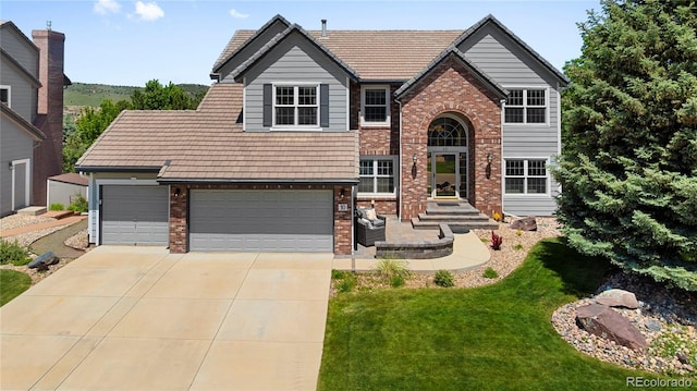 10 Sand Cherry, Littleton, CO 80127 - view of front of house with brick siding, concrete driveway, and a front yard