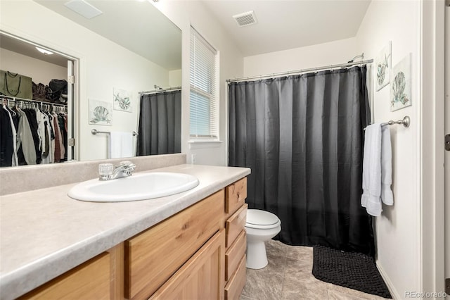 933 W Independent Ave, La Salle, CO 80645 - bathroom featuring visible vents, vanity, toilet, a walk in closet, and tile patterned floors