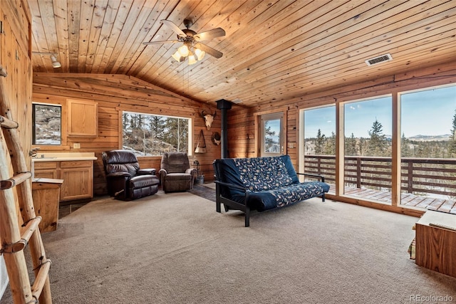 living room with lofted ceiling, carpet floors, wood walls, wood ceiling, and visible vents