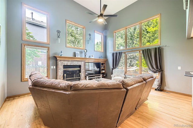 6588 S Oak Cir, Littleton, CO 80127 - living area featuring light wood-type flooring, ceiling fan, a glass covered fireplace, and a high ceiling