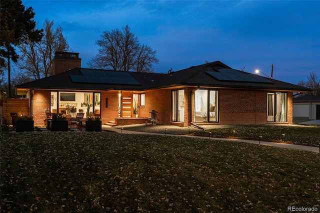 rear view of property with an outdoor living space, a yard, a patio, and solar panels